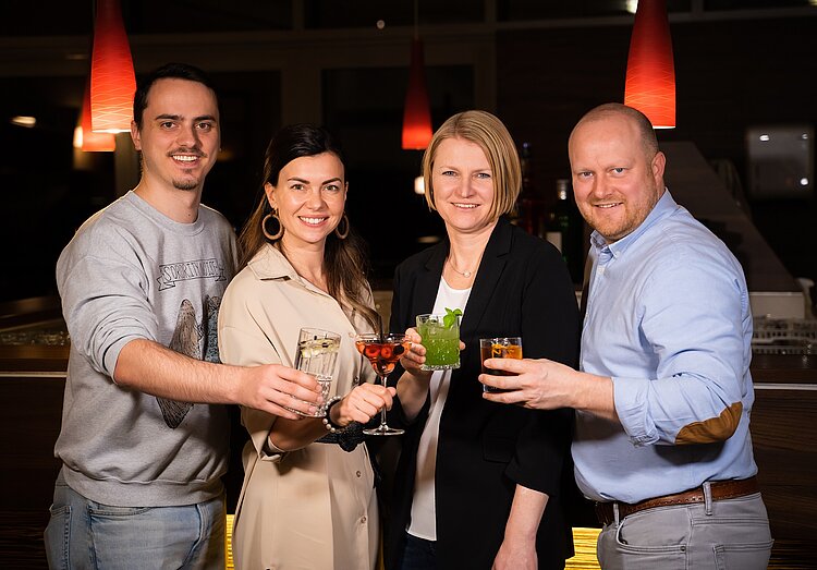 Eine Gruppe von vier Personen steht mit Cocktails an der Hotelbar im Hotel Liebmann