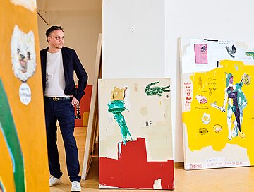 Jimmy Zurek posiert neben seinen Gemälden. 