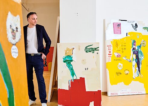 Jimmy Zurek posiert neben seinen Gemälden. 